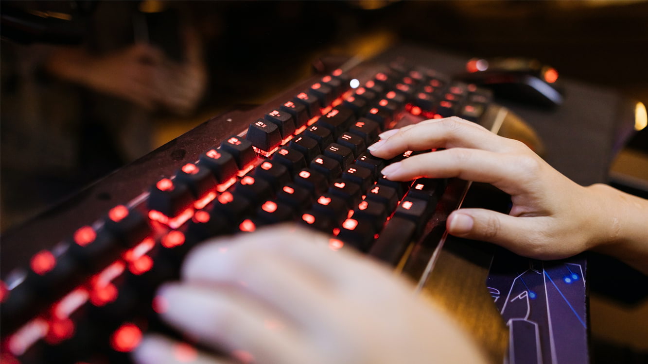 Mãos tocando um teclado gamer.