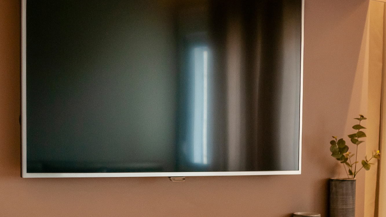 TV plana colocada em uma parede bege.