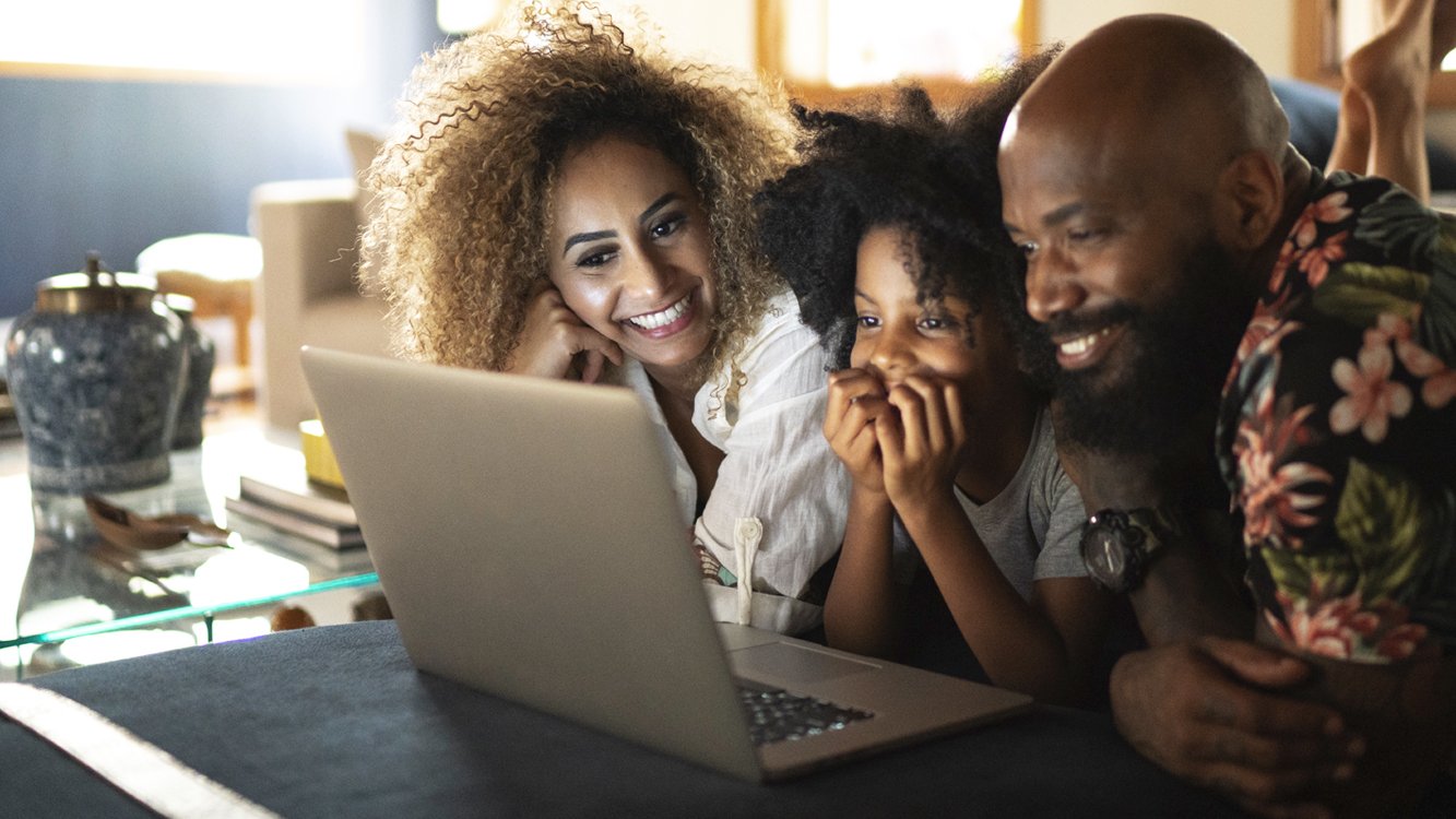 Família sorrindo em frente a um notebook