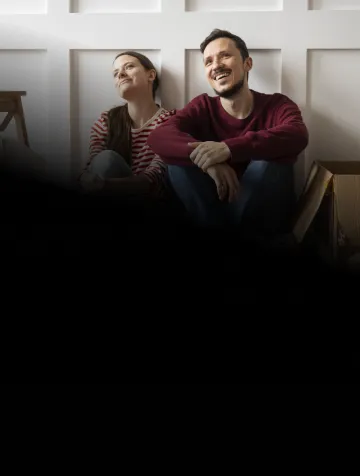 Casal sentado no chão com caixas ao redor em meio uma mudança de endereço e felizes sabendo que Oi Fibra vai com eles.