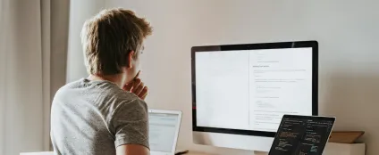 De costas, homem usa computador e laptops pra trabalhar home office