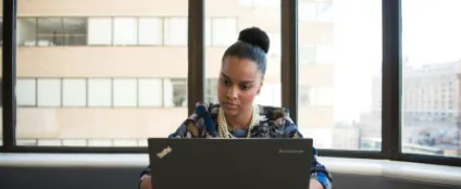 Sentada em um escritório, mulher usa um computador conectado ao Wi-Fi da internet empresarial Oi Fibra 
