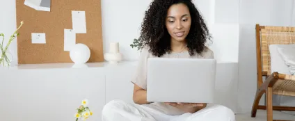 Na sala de casa, mulher trabalha em um laptop conectado à internet Oi Fibra
