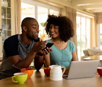 Homem em casa, enquanto usam um smartphone e celular conectados ao Wi-Fi da Oi Fibra