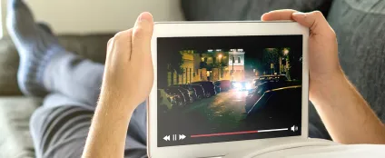Pessoa assiste a filme online em seu tablet com a internet Oi Fibra