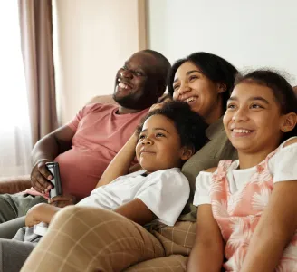 Família acompanha filme online sentados no sofá da sala e conectados à internet fibra ótica