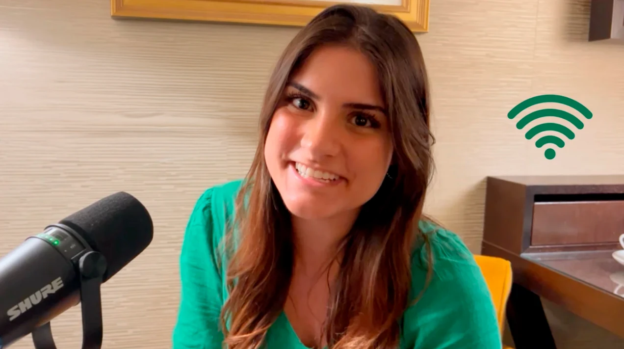 Uma mulher sorridente com um microfone de mesa conversando online usando  o melhor plano de internet para casa.