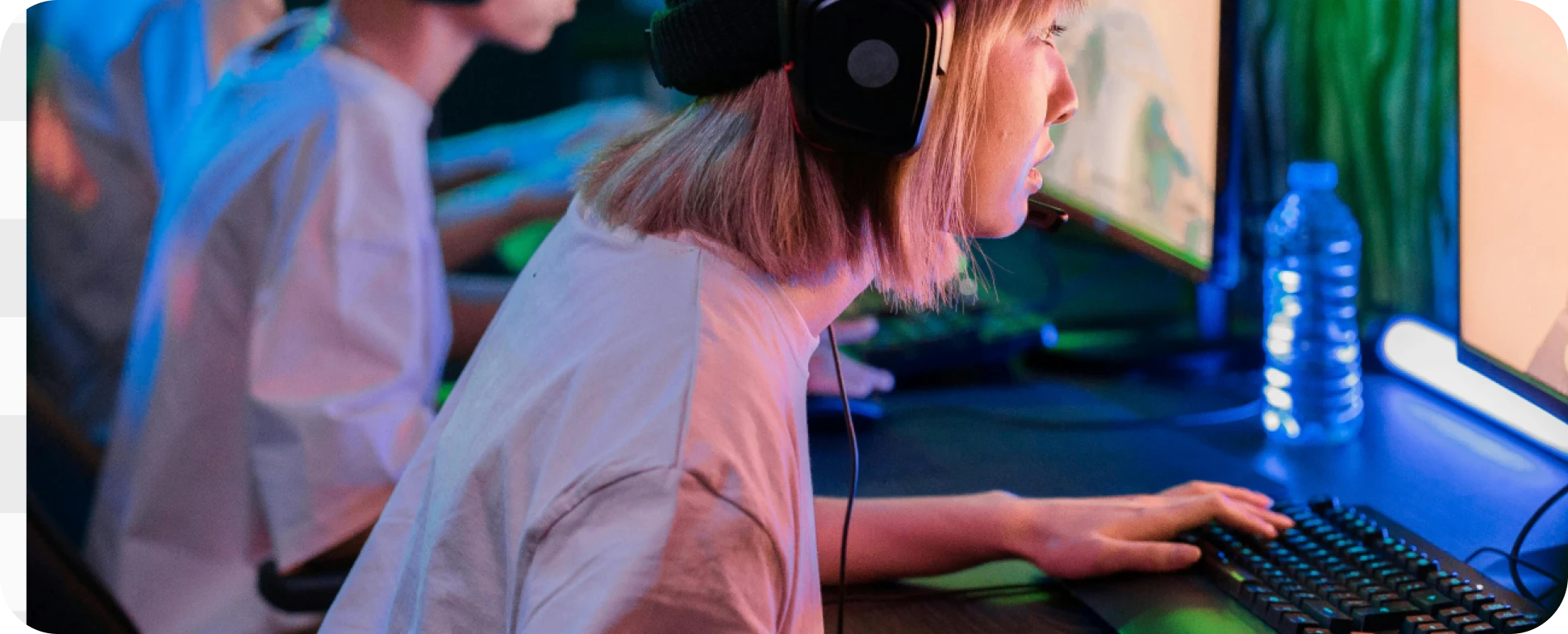 Uma pessoa gamer concentrada em frente ao monitor com fones de ouvido, jogando online com a melhor internet gamer.
