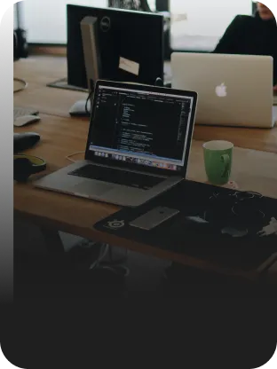 Ambiente de trabalho moderno com notebook sobre a mesa com código em tela em ambiente colaborativo conectado com Oi Fibra.