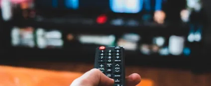 Pessoa usa controle remoto enquanto assiste a séries e filmes online em Smart TV