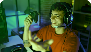 Um jovem está de headset e joystick na mão sorrindo e jogando online