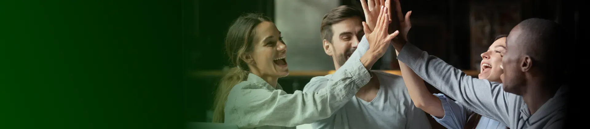 Foto de quatro pessoas num escritório de trabalho fazendo high five e comemorando
