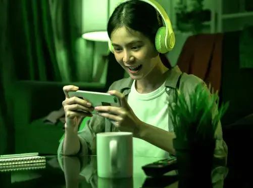 Mulher com celular e fone de ouvido gamer conectada com internet Oi Fibra