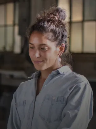 Acesse a página do Programa de conformidade da Oi. Funcionária de camisa social e cabelos presos.