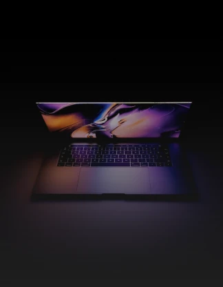A imagem mostra um notebook com a tela entreaberta  no fundo escuro