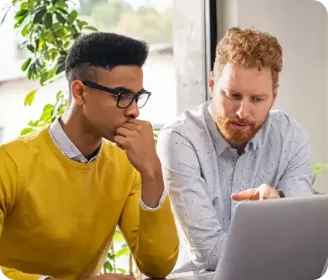 Dois homens estão focados trabalhando em um laptop.