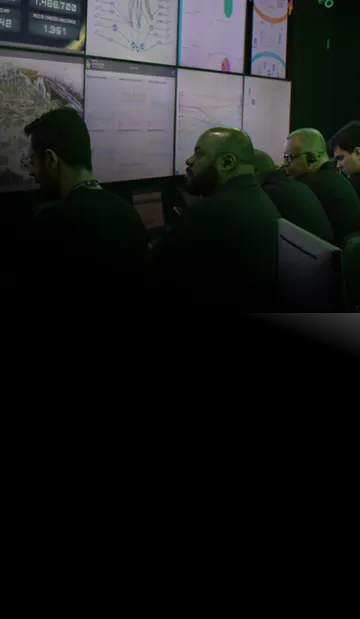 Sala de controle de segurança cibernética com vários monitores exibindo dados e equipe de analistas trabalhando.