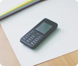Celular simples de botão preto sobre uma folha de papel branca