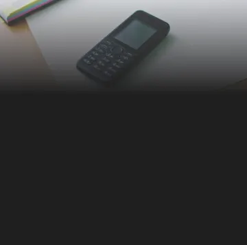 Celular simples de botão preto sobre uma folha de papel branca