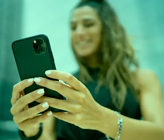 Mulher segurando um smartphone e olhando para a tela com um sorriso